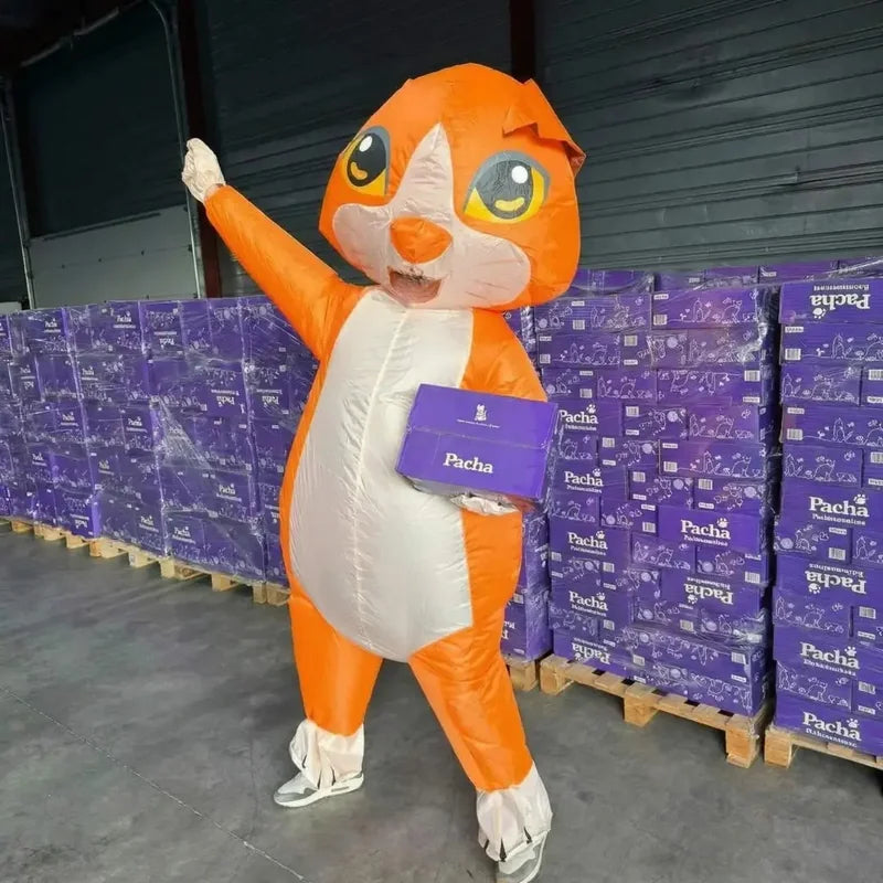 Das Pacha-Maskottchen mit einer Packung Streu vor Paletten mit Spenden für Tierheime